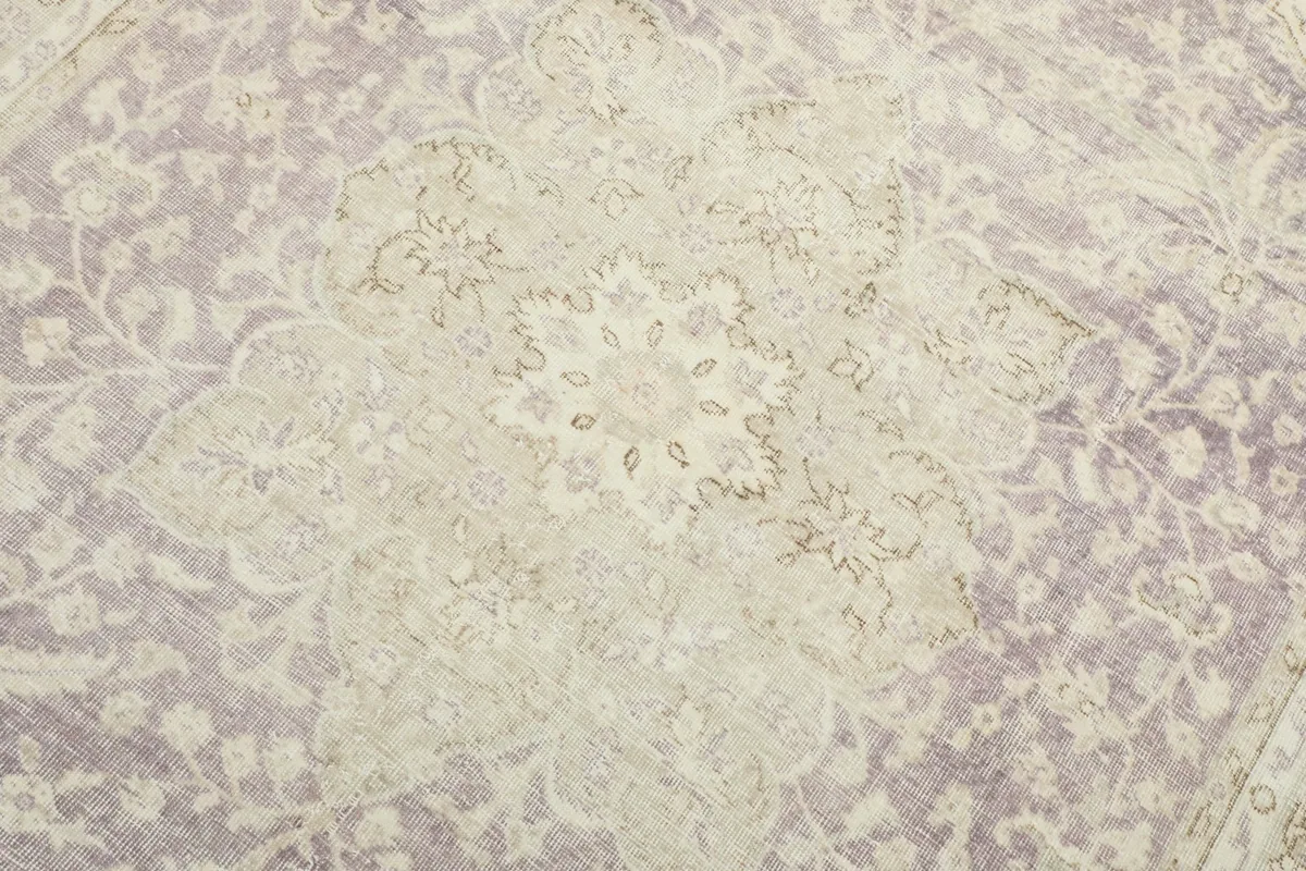 Detailed close-up of the central medallion, revealing the subtle purple and beige colors and wool texture.