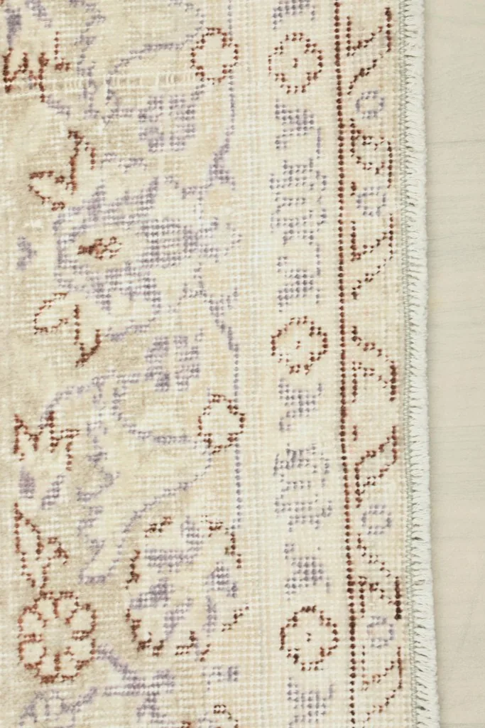 Detail of the rug's edge, showing the decorative border pattern and short fringe.
