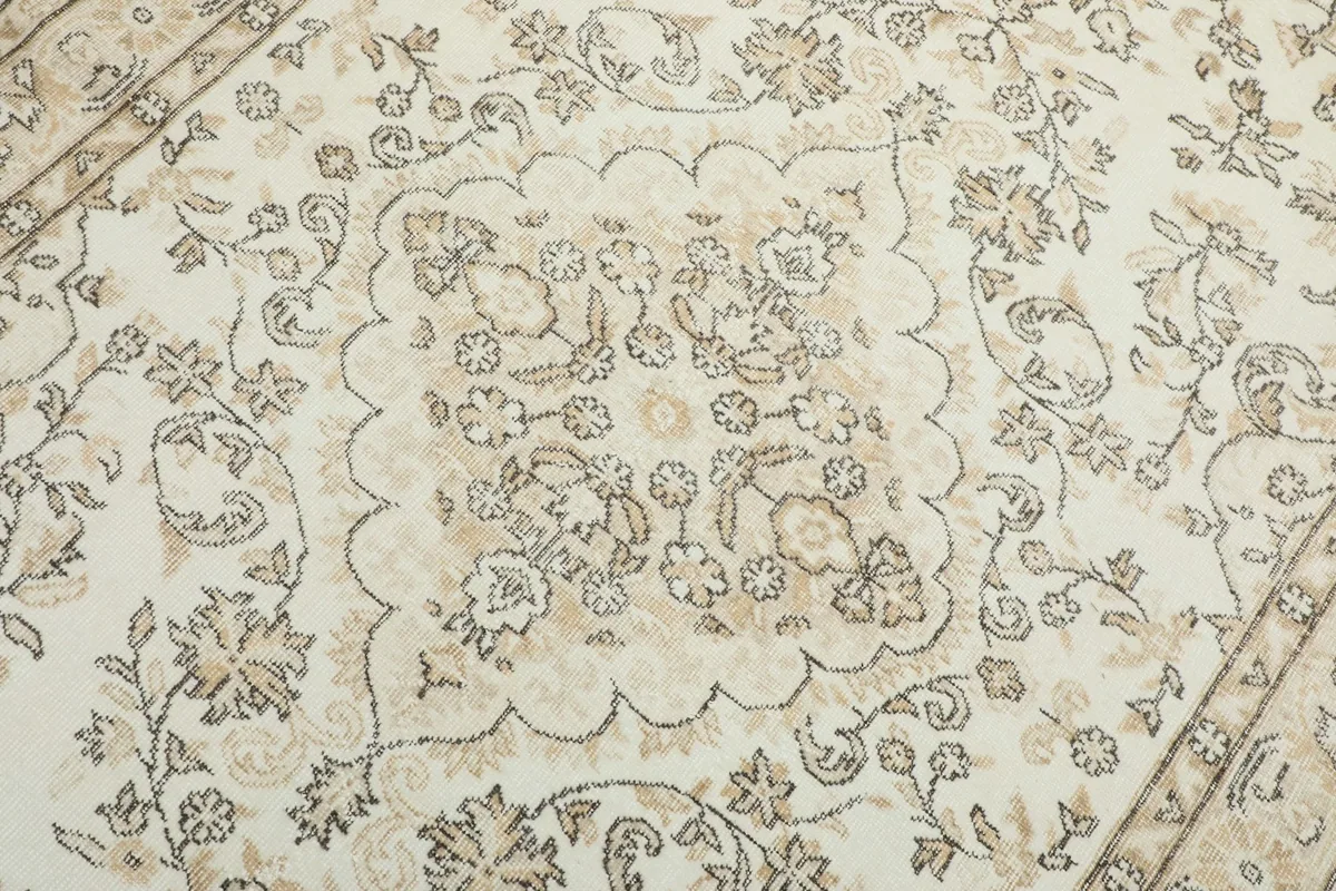 Detailed view of the central medallion and surrounding floral motifs on the ivory field of the rug.