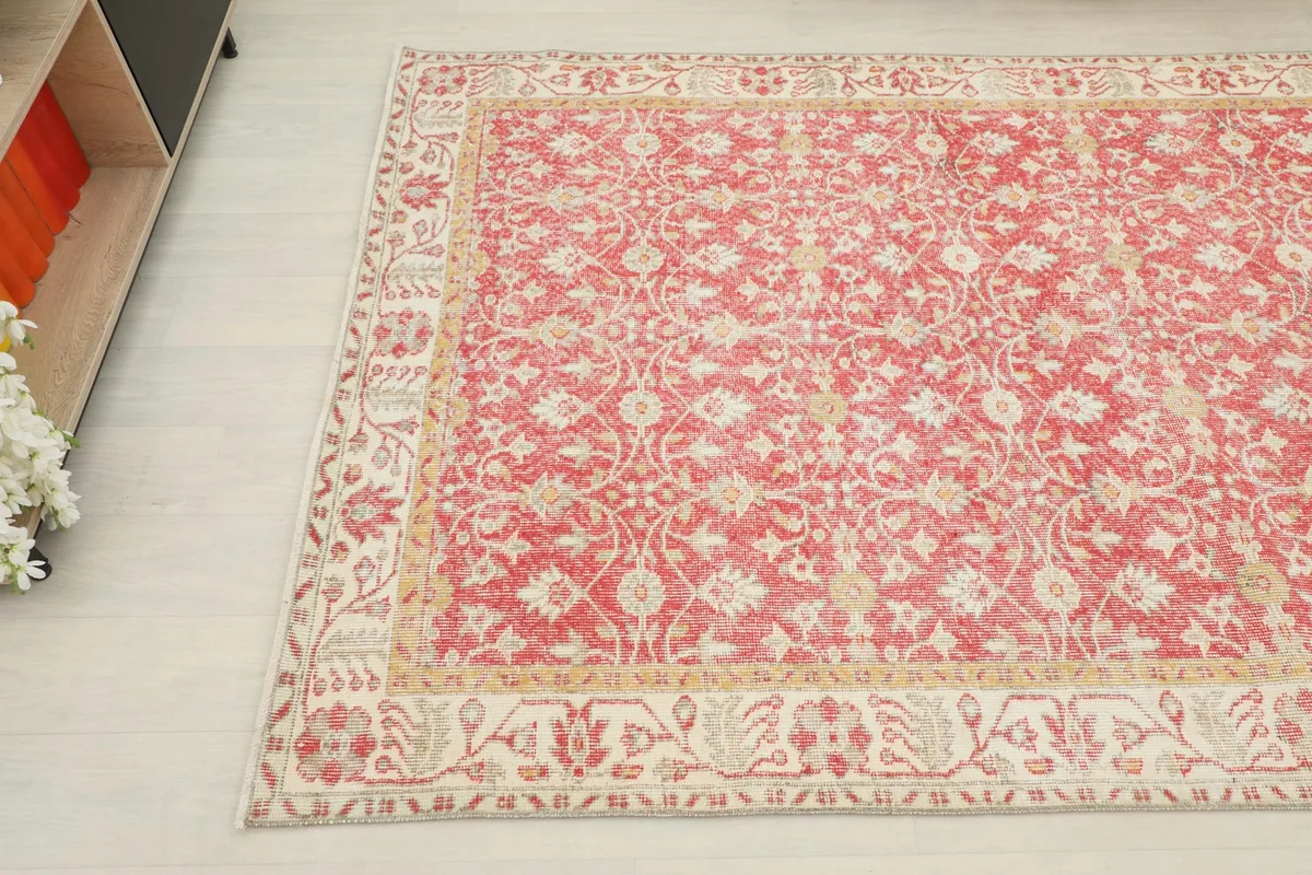 Detailed corner view of the red rug, highlighting the intricate floral and geometric patterns.