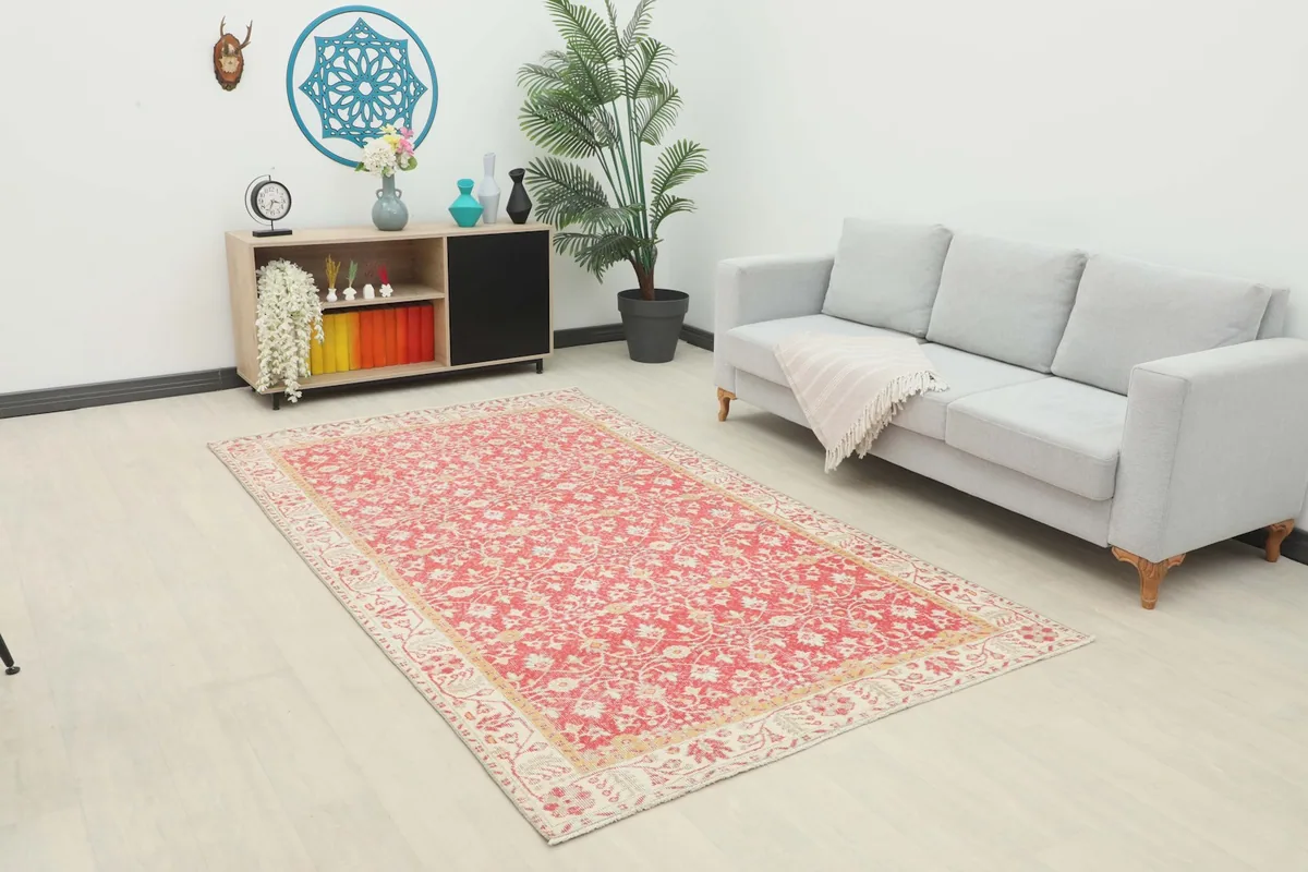 Vintage Anatolian rug with red floral pattern in a modern living room setting with a gray sofa.