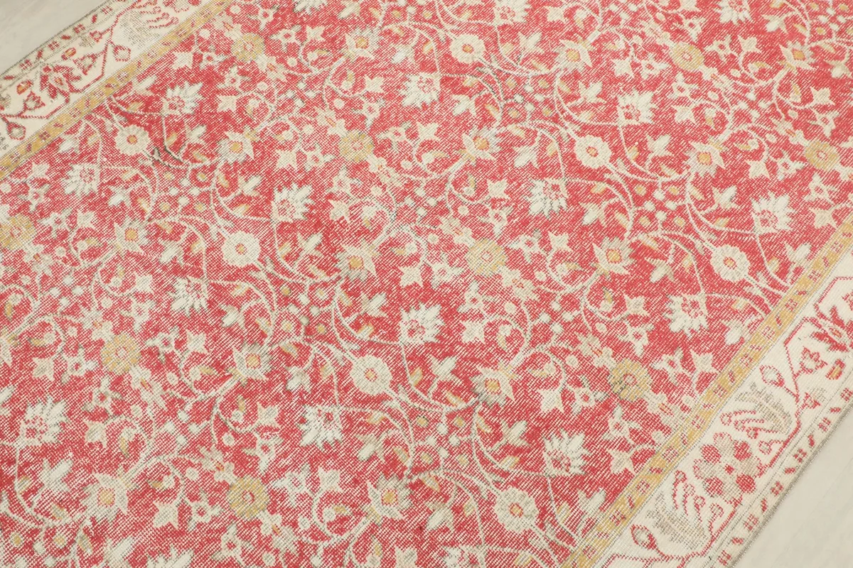 Overhead detail showing the red field with ivory and beige floral motifs and faded patina.