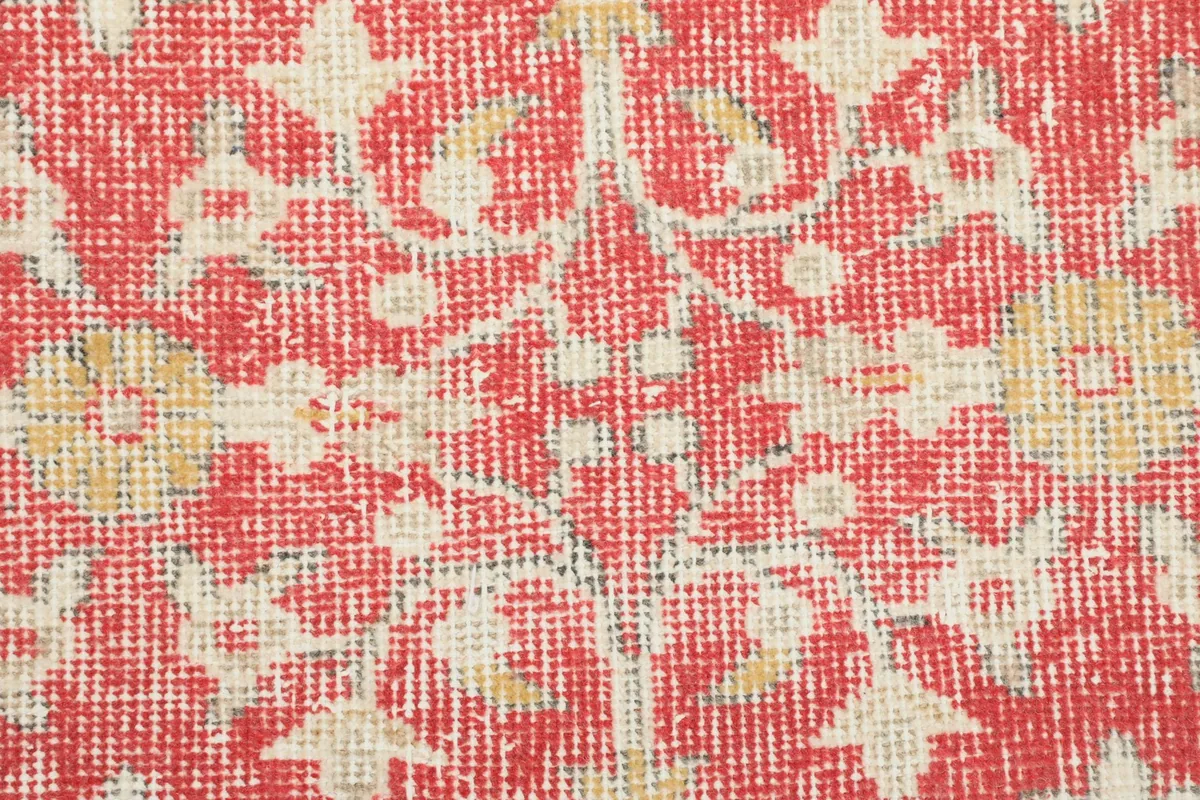 Close-up of the wool pile, showing the hand-knotted texture and subtle color variations in red and ivory.