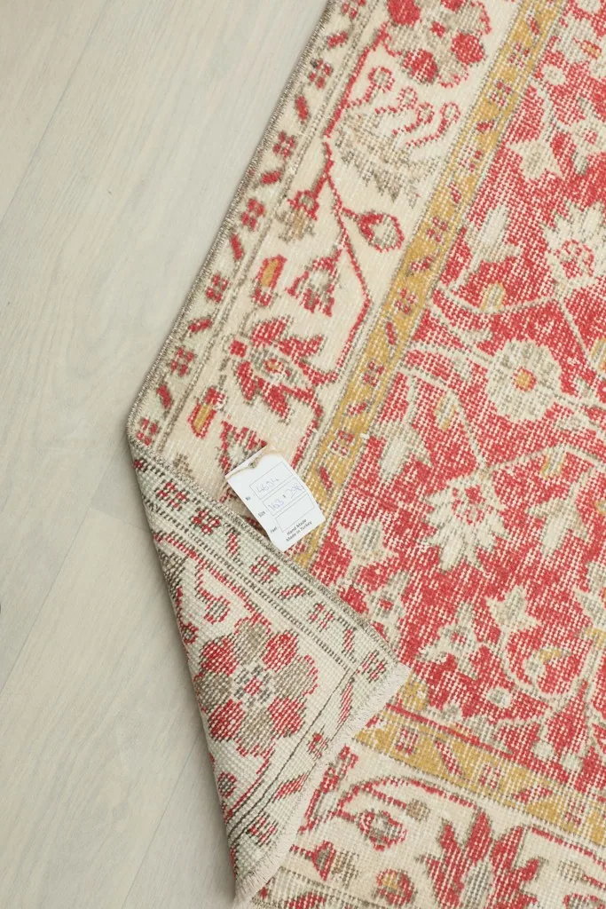 View of the back of the rug where a label is attached, showing the tightly woven cotton foundation.