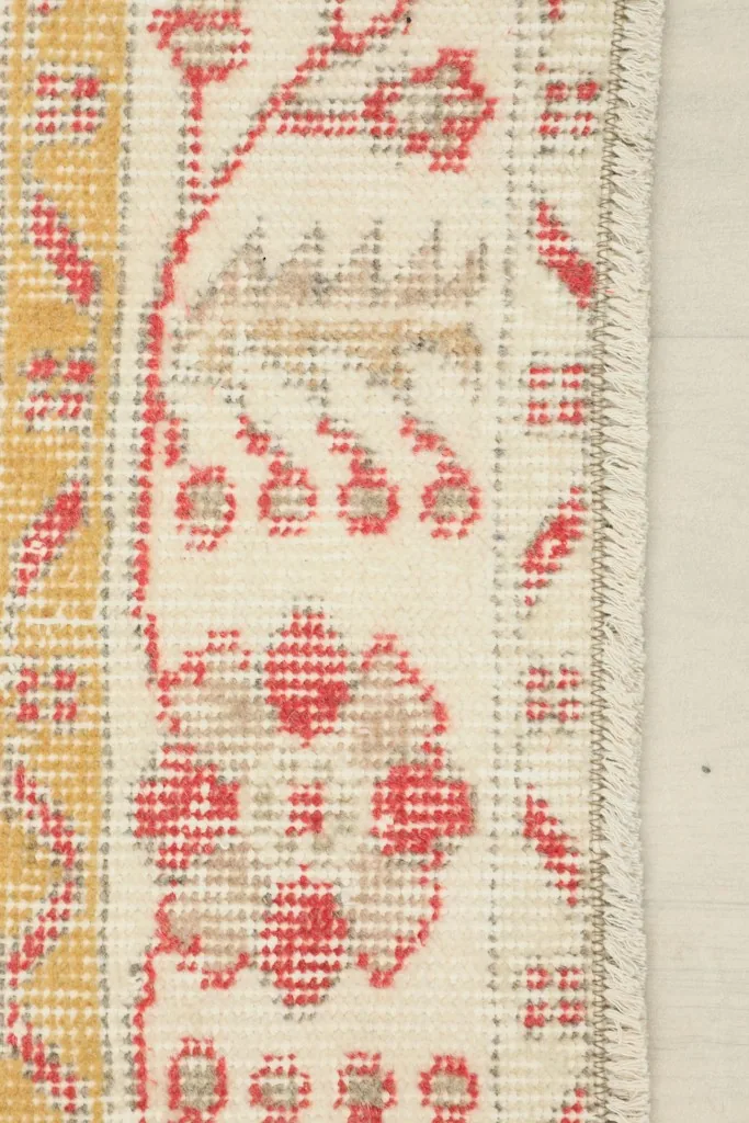 Detail of the rug's edge, showcasing the ivory border design and the short, finished fringe.