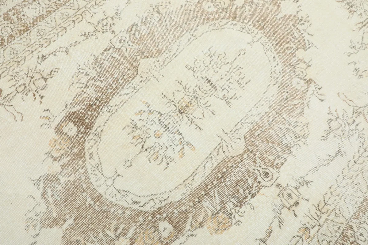 Close-up detail of the central medallion and floral motifs in shades of tan and brown.
