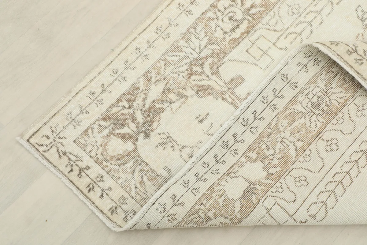 The corner of the rug folded back, revealing the reverse side and hand-knotted construction.