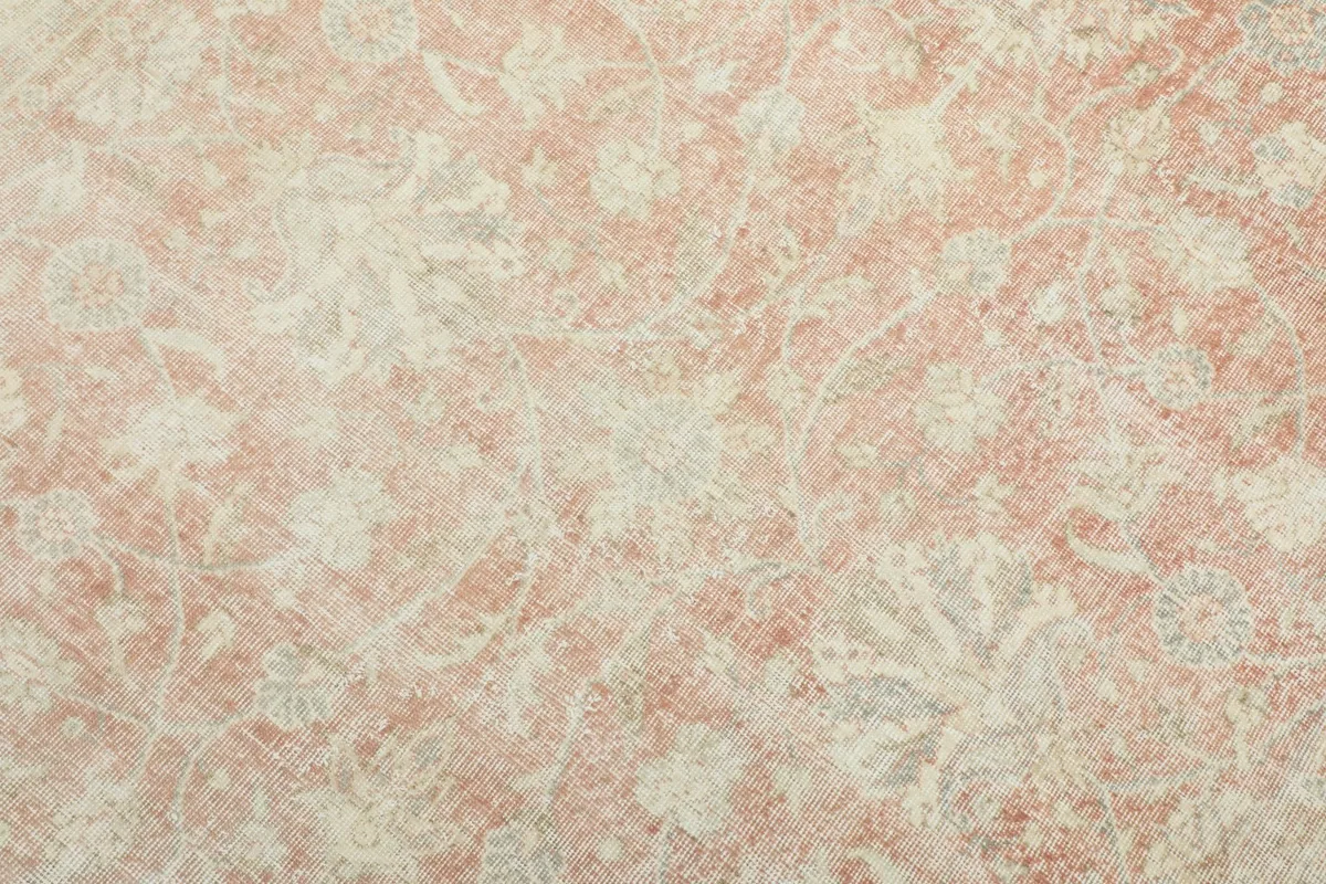Detailed close-up of the faded floral patterns and texture within the rose field of the hand-knotted rug.