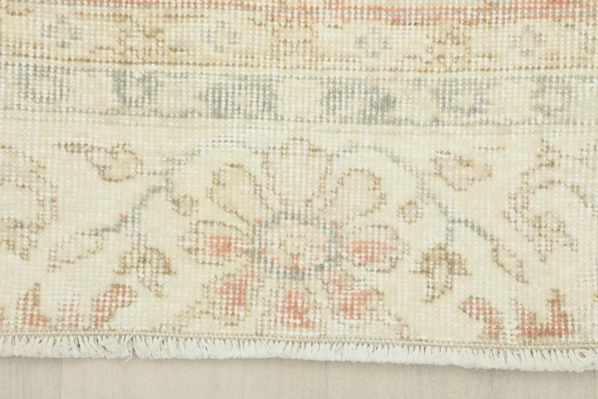 Close-up of the cream border pattern and short, natural fringes at the edge of the vintage Anatolian rug.