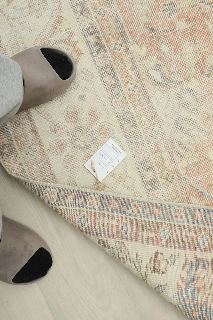 Underside view of the rug with a tag, showing the tightly woven cotton foundation and hand-knotted structure.