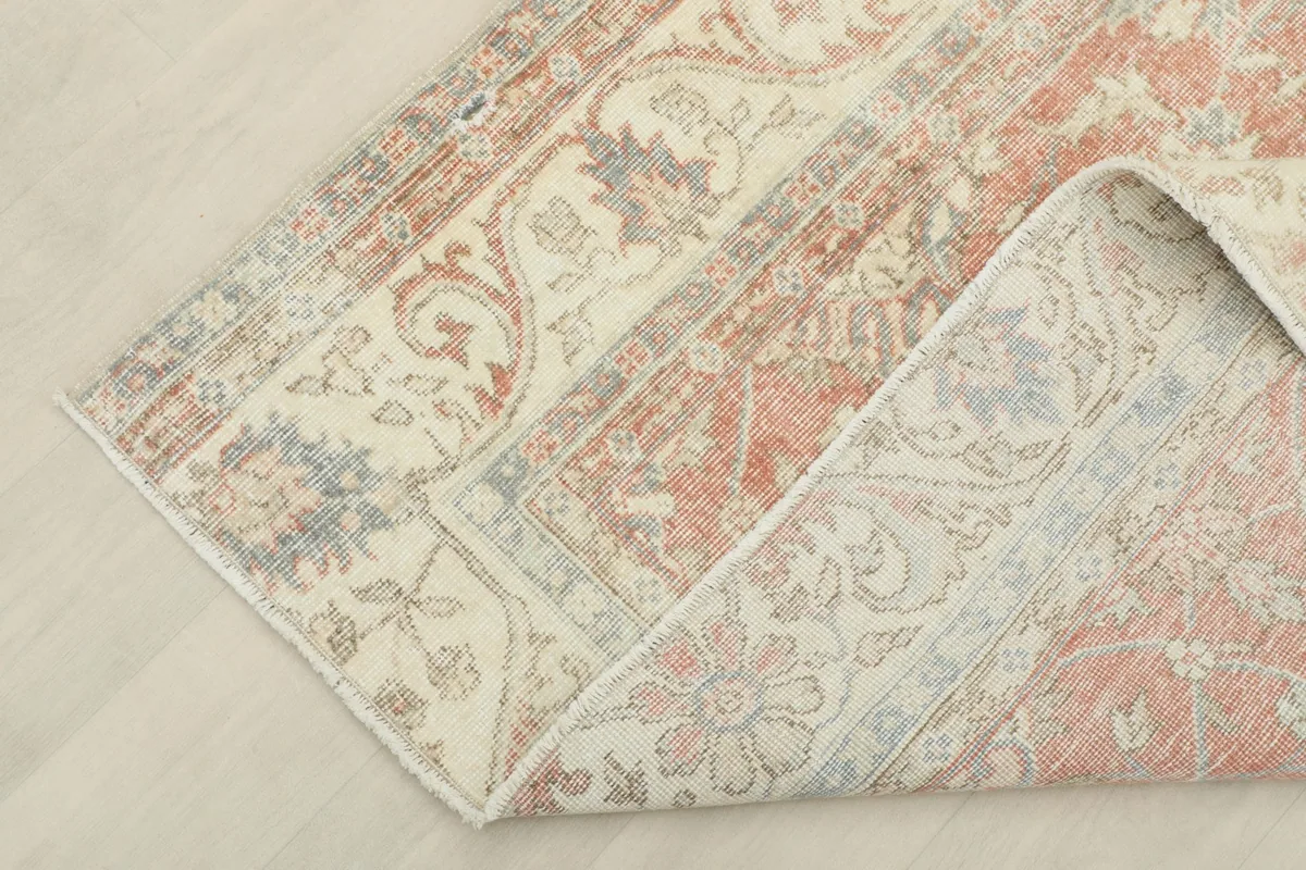 Corner of the rug folded back to show the cotton foundation and the reverse side of the hand-knotted construction.
