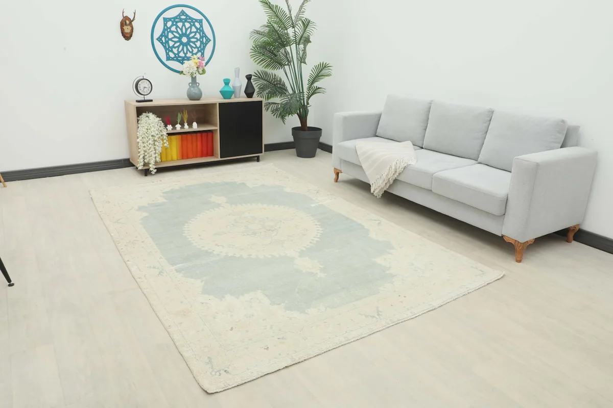 Vintage Anatolian rug displayed in a room setting with a light-colored sofa and wooden furniture.