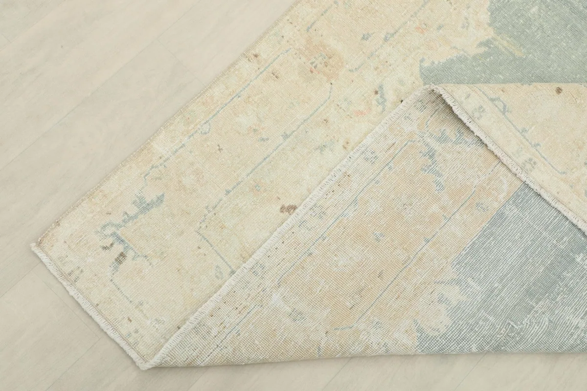 Corner of the rug folded back, revealing the cotton foundation and hand-knotted construction.