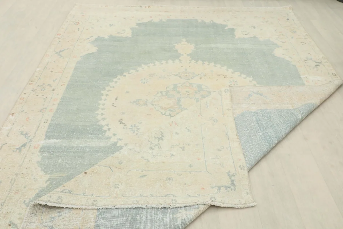 The rug partially folded, showing the reverse side and the texture of the wool pile on the front.
