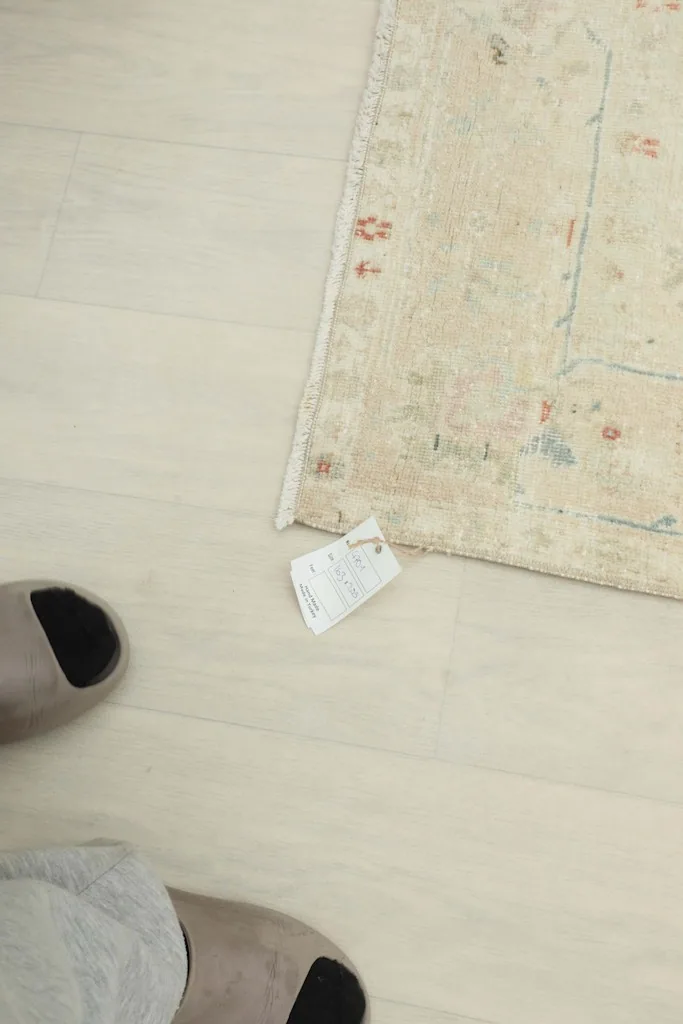 View of the rug's edge on the floor, with a small tag visible, showing the professional cleaning label.