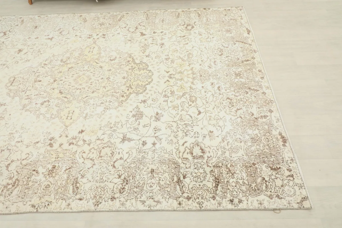 Close-up view showing the faded ivory and beige floral medallion patterns of the rug.
