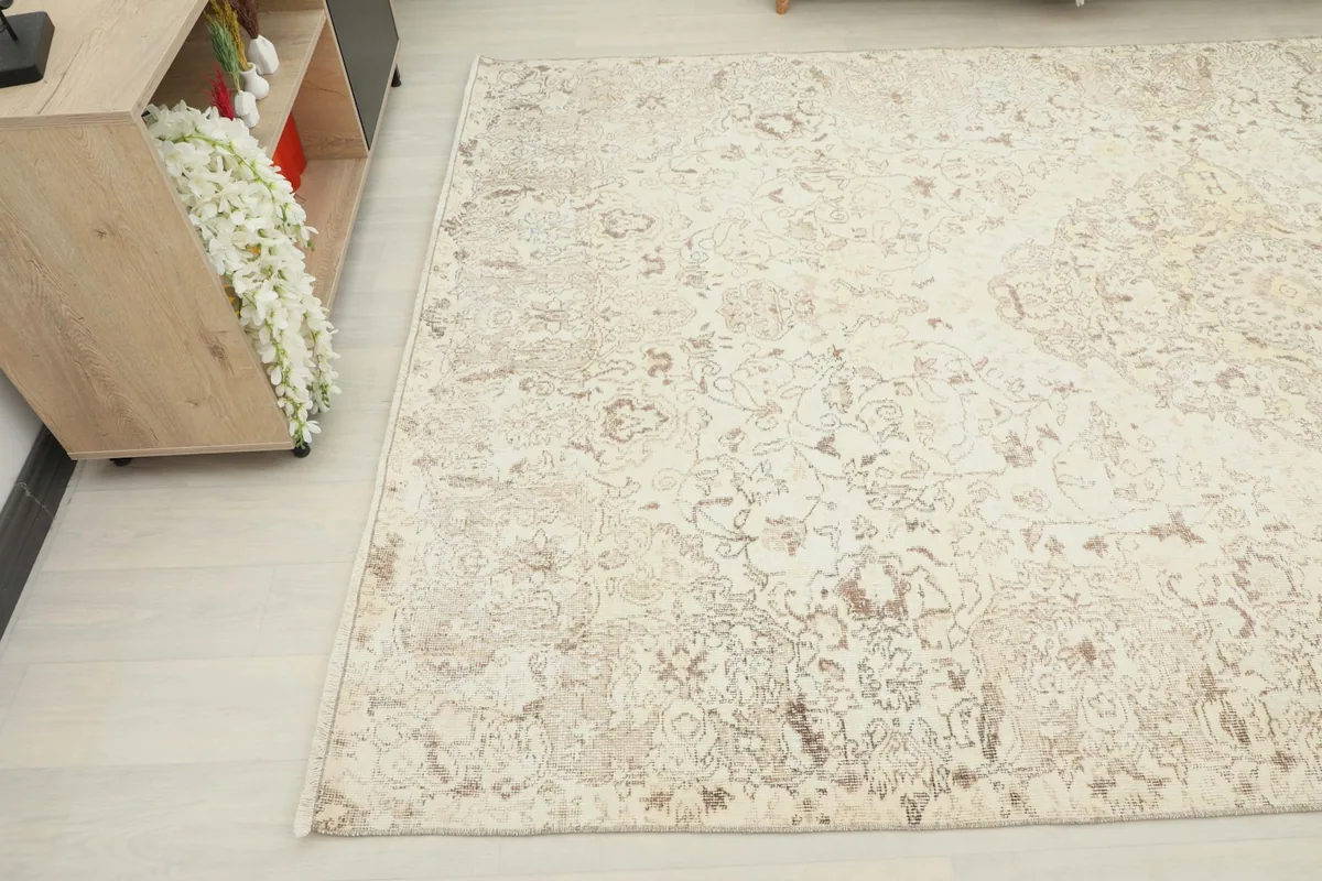Detailed view of the rug's surface, highlighting the distressed texture and beige motifs.
