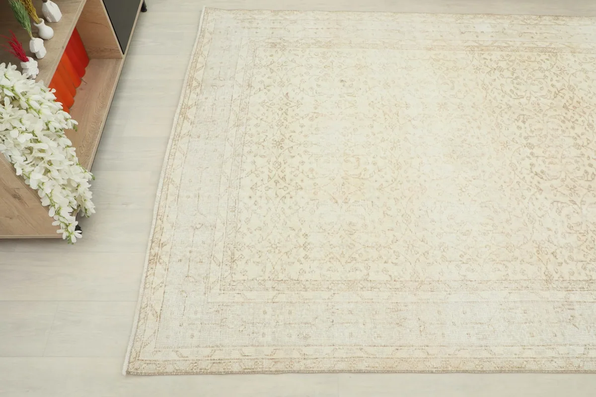 Close-up angled view of the cream and tan rug next to a light wood cabinet