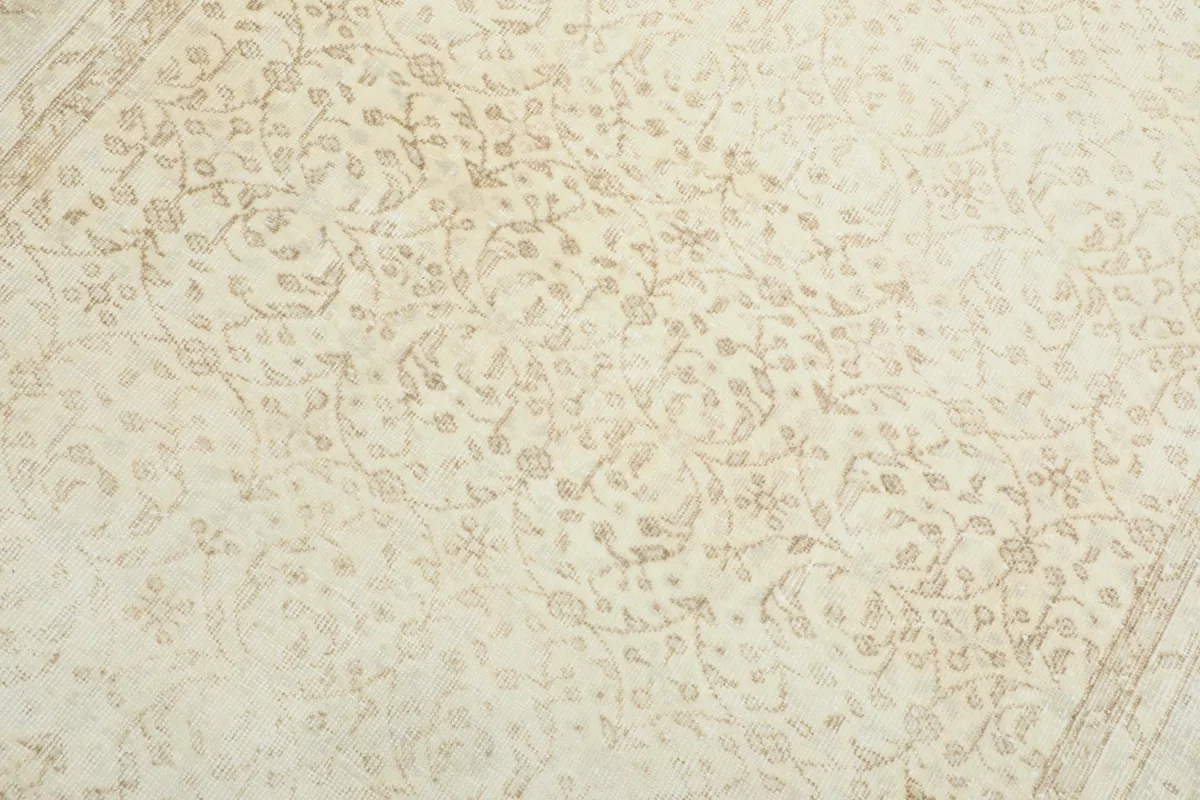 Detailed view of the intricate tan floral motifs on the cream field of the rug