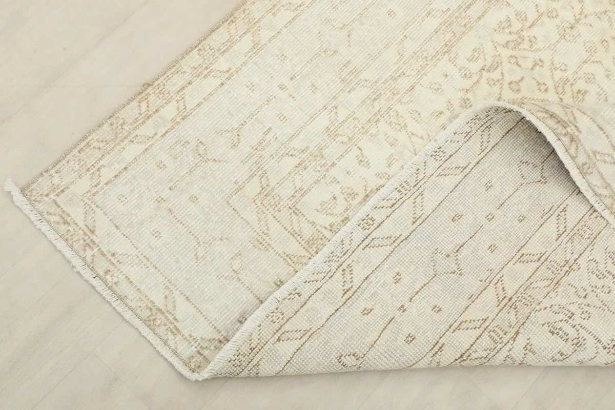 Corner of the rug folded back to reveal the cotton foundation and reverse side