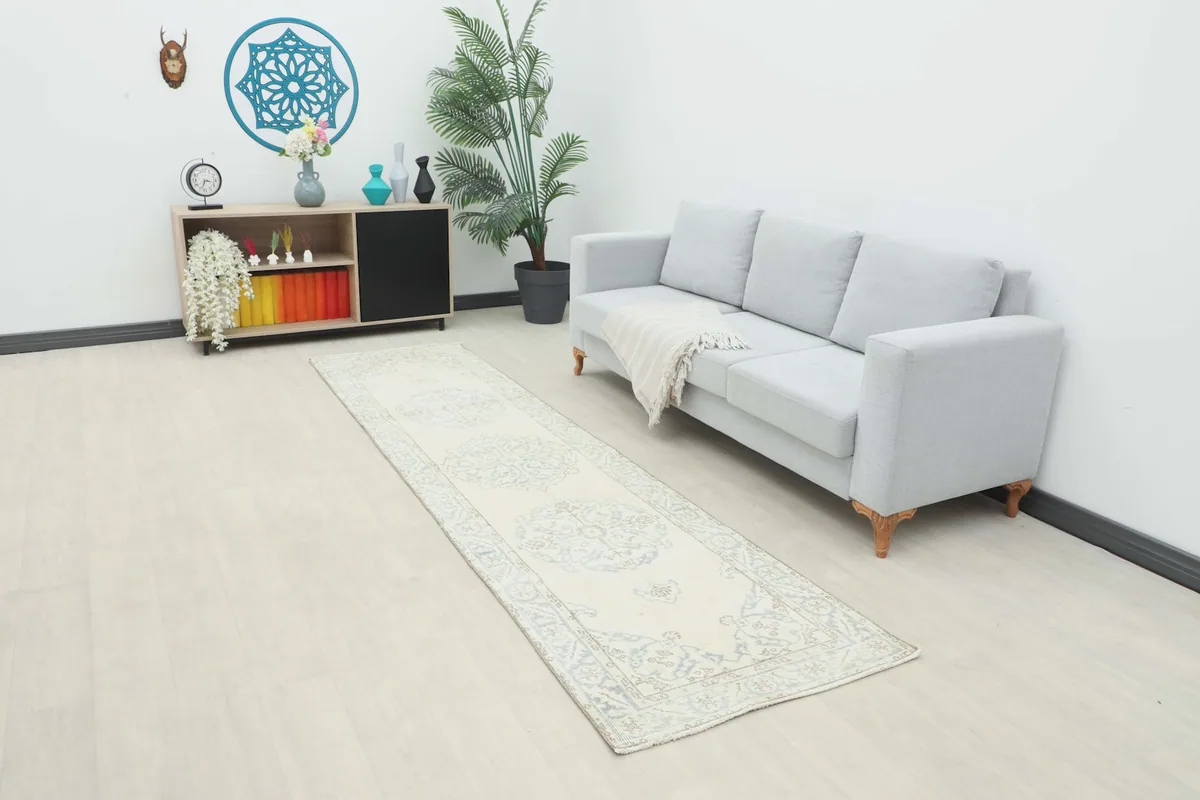 Vintage Anatolian runner rug laid out in a living room setting next to a light gray sofa.