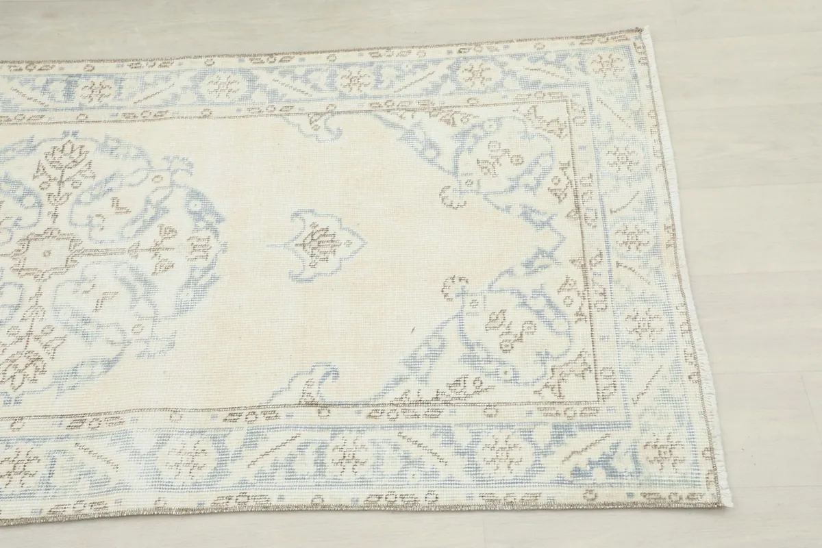 Close-up detail of one end of the runner, highlighting the ivory field, blue medallion, and border.