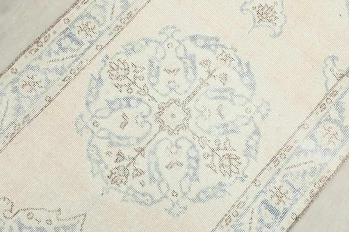 Detailed overhead shot of a central blue medallion motif and surrounding ivory field.
