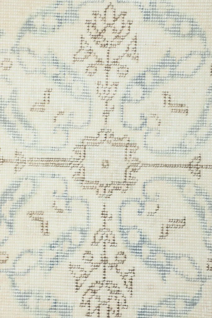 Extreme close-up of the rug's low wool pile, revealing the hand-knotted texture and faded colors.