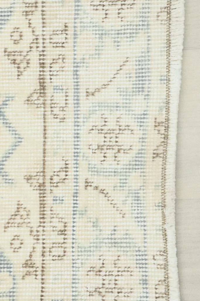 Close-up of the rug's edge, showing the hand-knotted structure and minimal fringe.