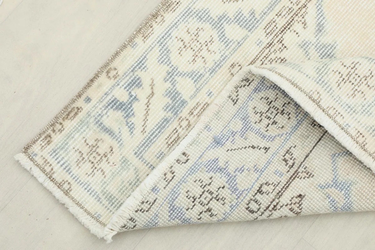 Corner of the runner folded back to show the cotton foundation and reverse side of the knotting.