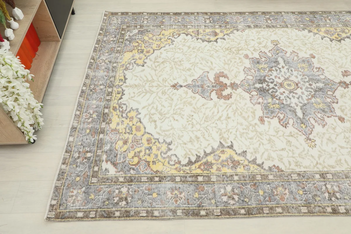 Close-up angled view of the rug's corner, showing the gray border and gold accents.