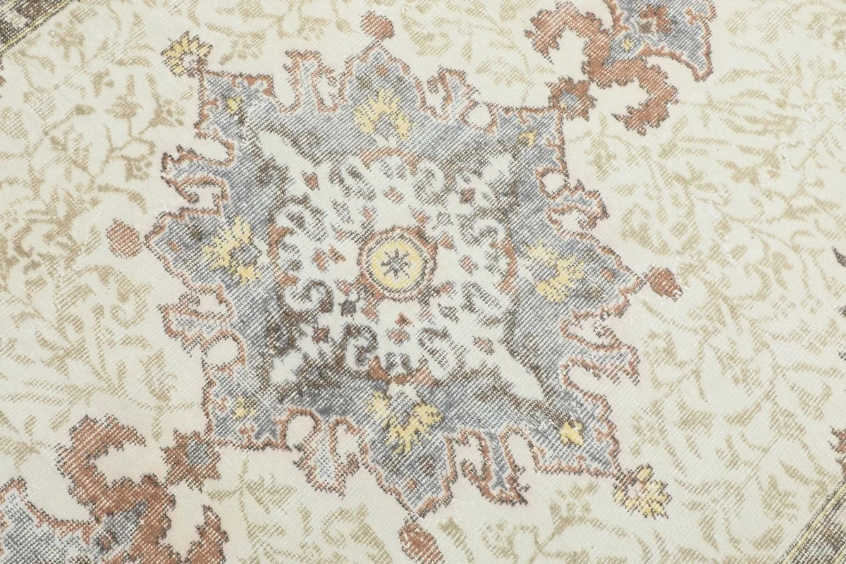 Detailed view of the rug's central medallion, featuring gray, rust, and gold colors.