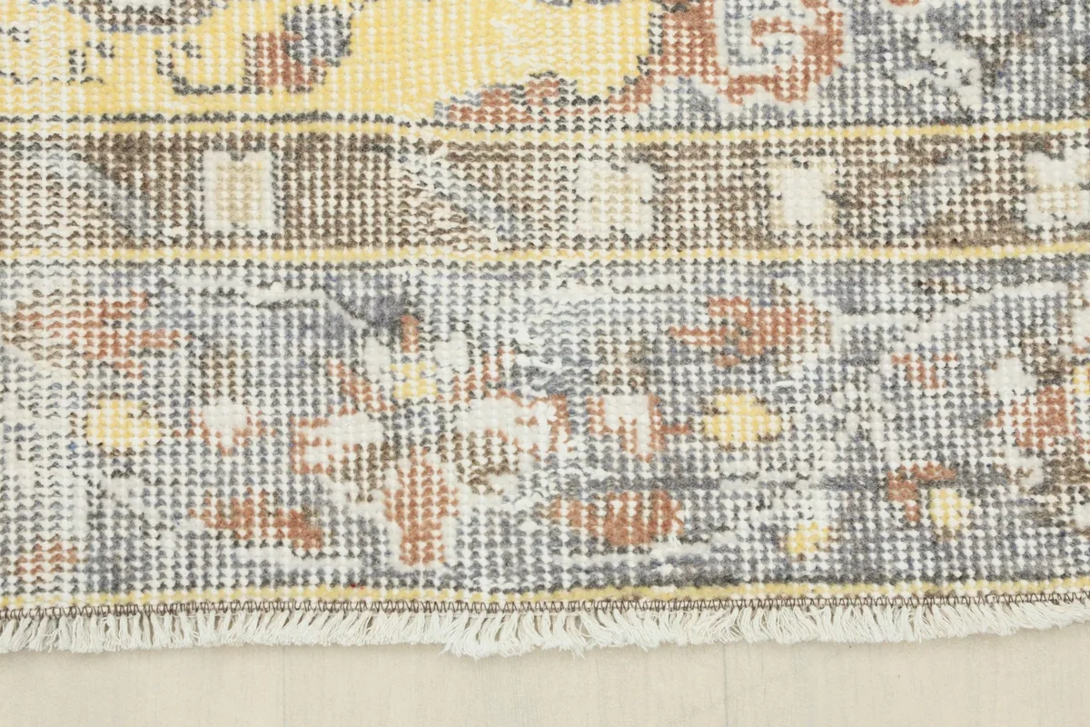 Close-up of the short fringes and the distressed gray border of the rug.