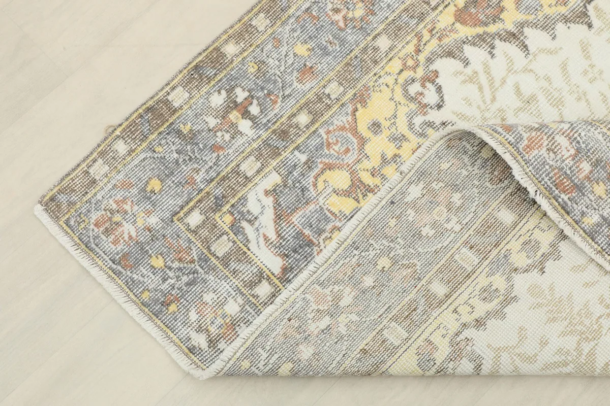 Corner of the rug folded back, showing the cotton foundation and the reverse side.