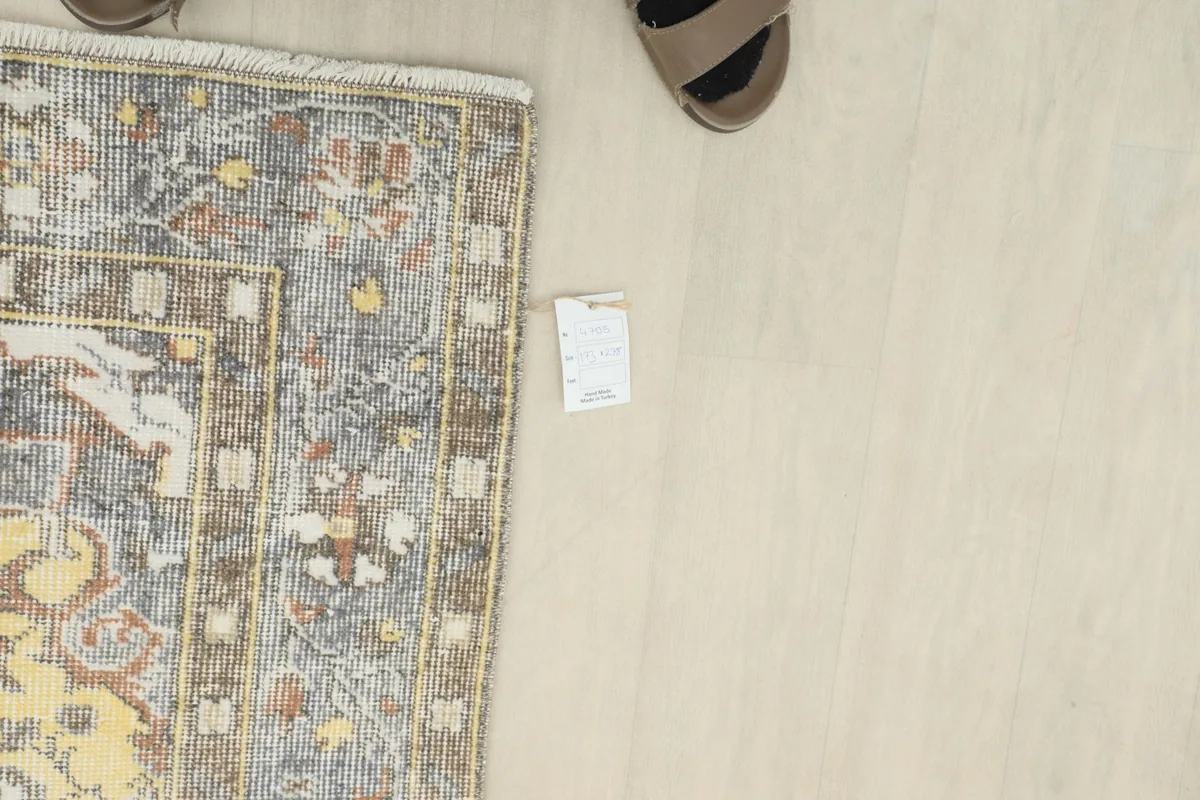 Overhead view showing the rug with a size tag and part of a foot, indicating scale.