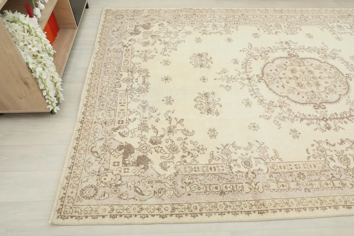 Corner view of the rug on a light floor, showing the subtle patina and floral motifs.