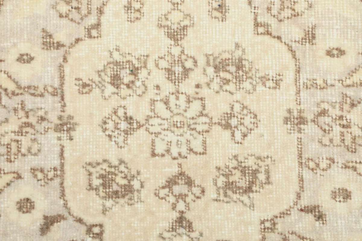 Close-up of the wool pile and intricate beige floral motifs within the rug's design.