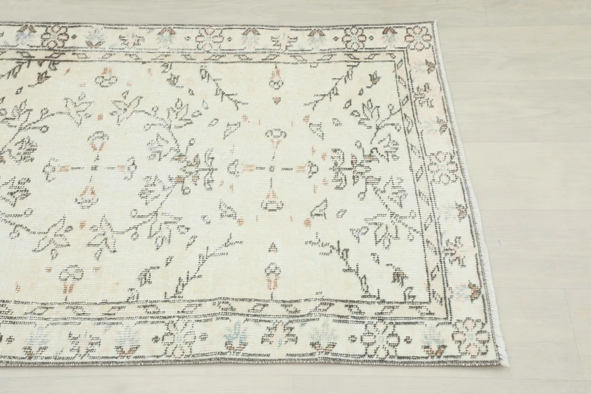 Close-up of the rug's ivory field and gray floral and vine motifs with subtle rust accents