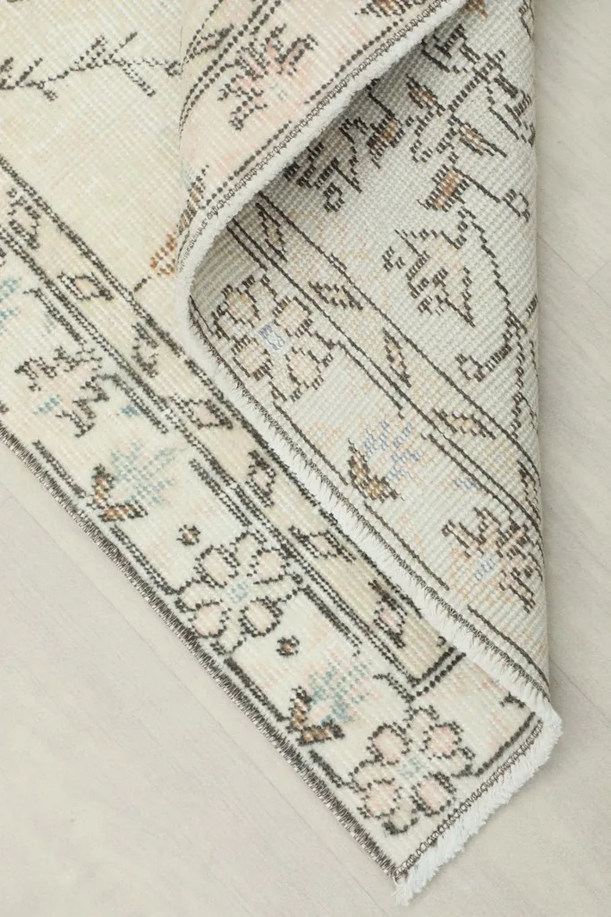 Corner of the rug folded back, revealing the reverse side of the hand-knotted construction