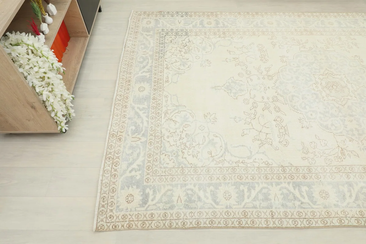 Close-up corner perspective of the rug, showing the intricate gray and beige border design