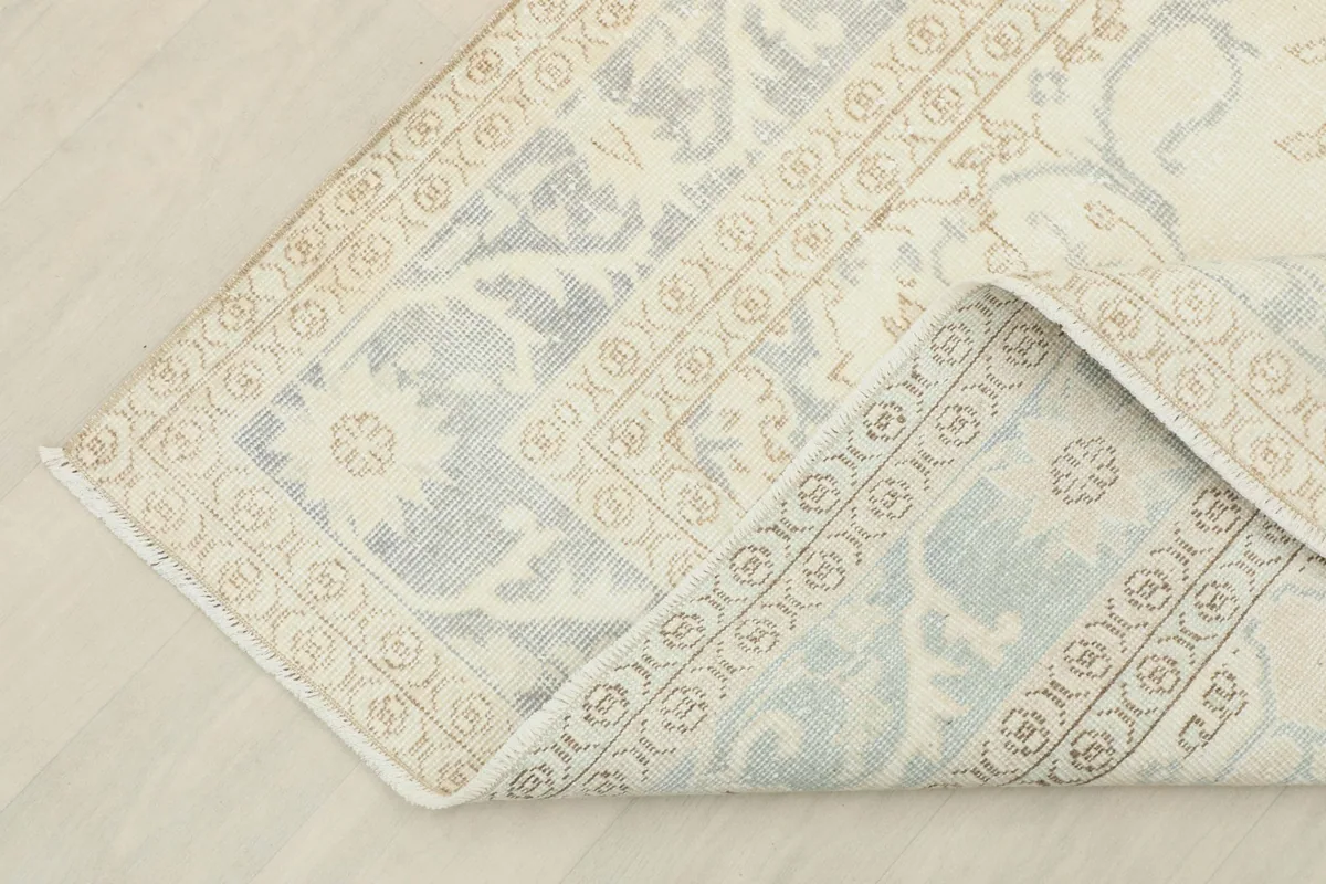 Corner of the rug folded back, revealing the cotton foundation and reverse side