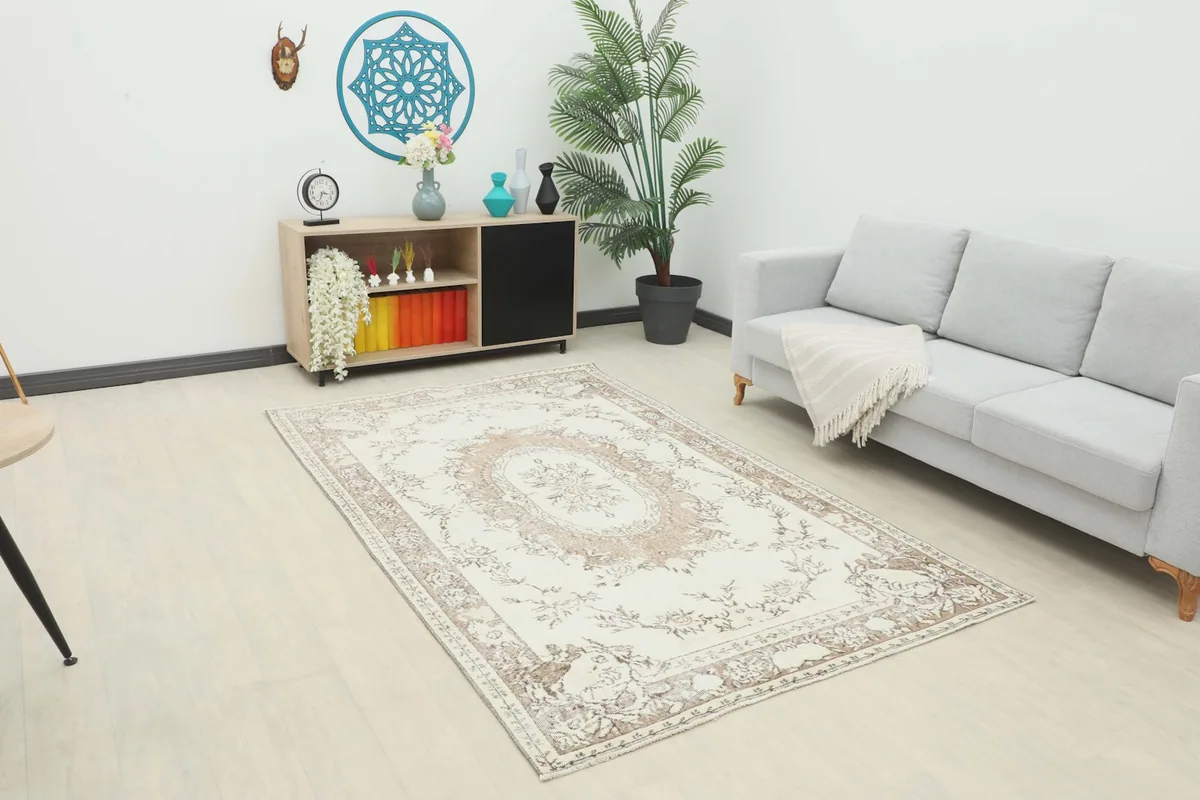 Vintage Anatolian rug placed in a living room setting, showing its scale next to a sofa and cabinet.