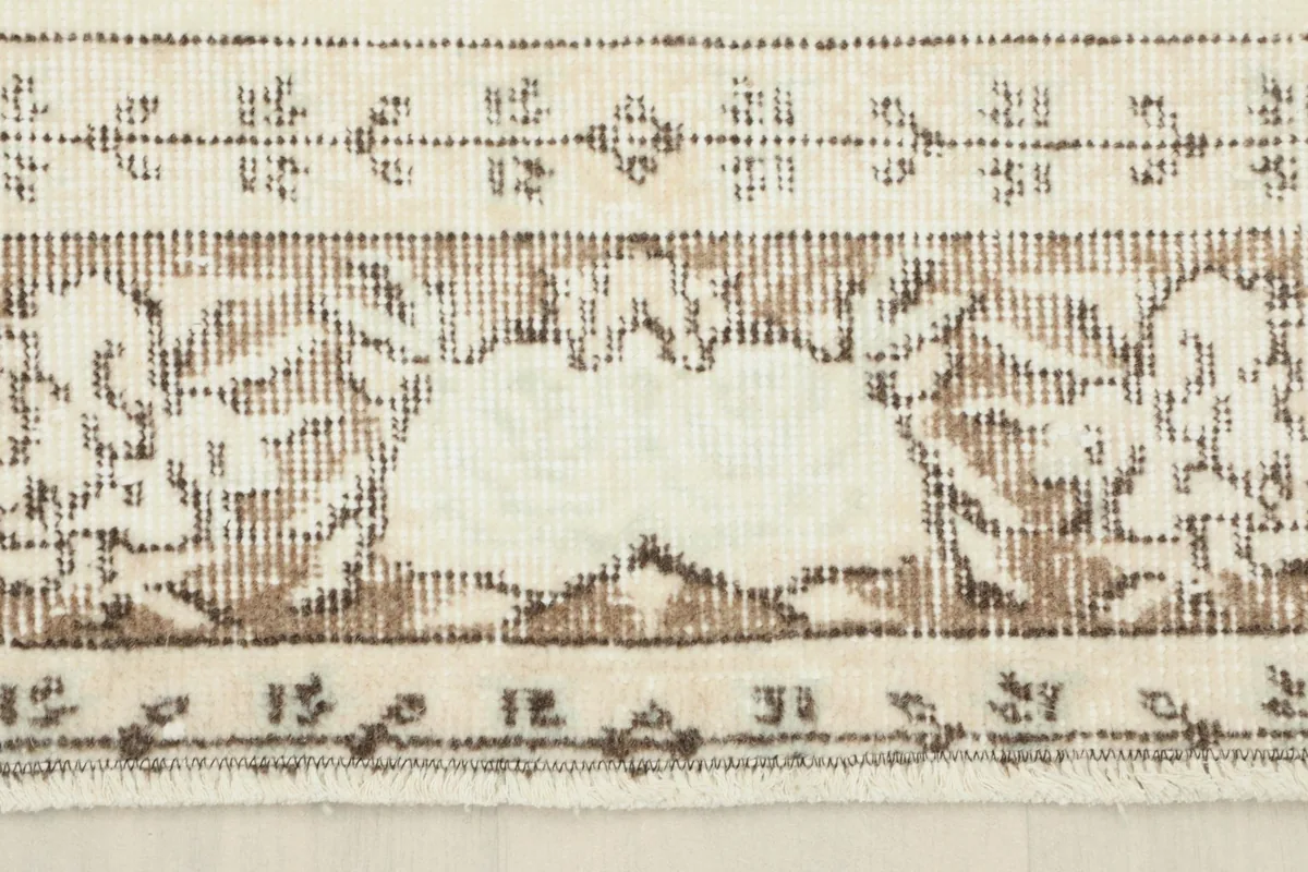 Close-up of the rug's outer border design with intricate brown patterns.