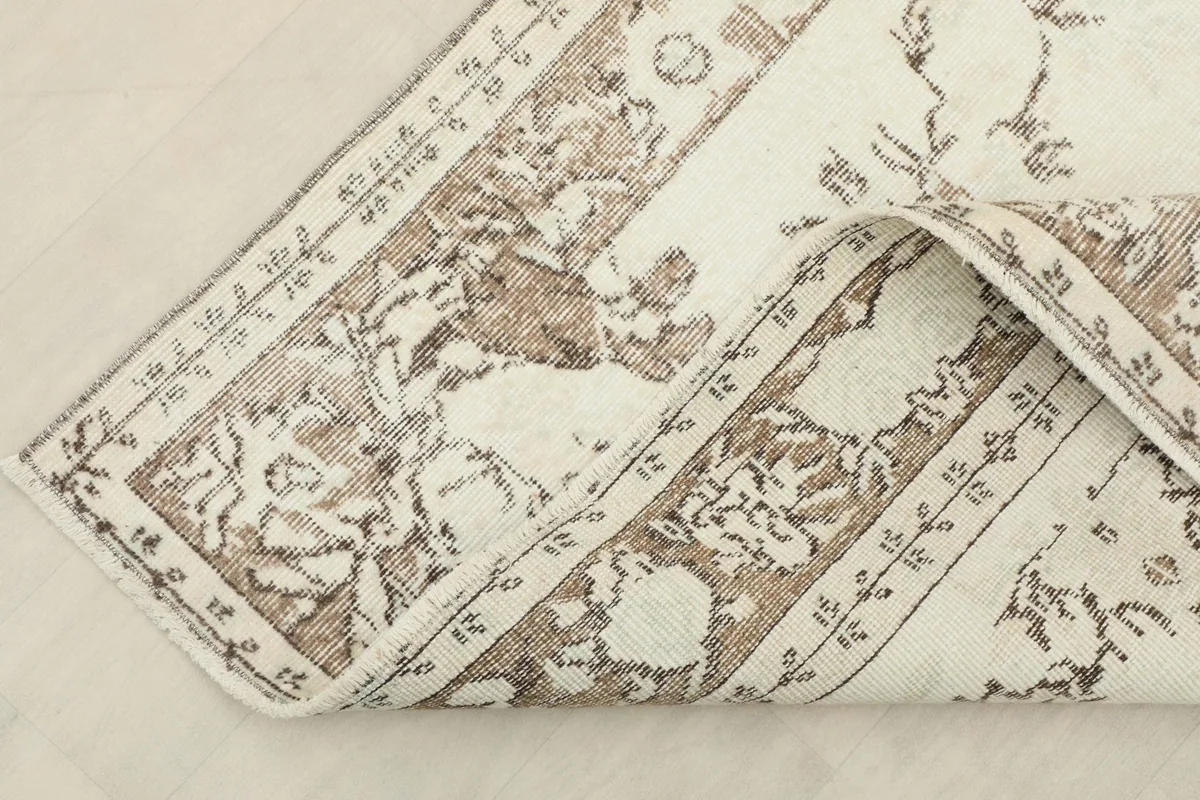 Corner of the rug folded back, revealing the reverse side and cotton foundation.