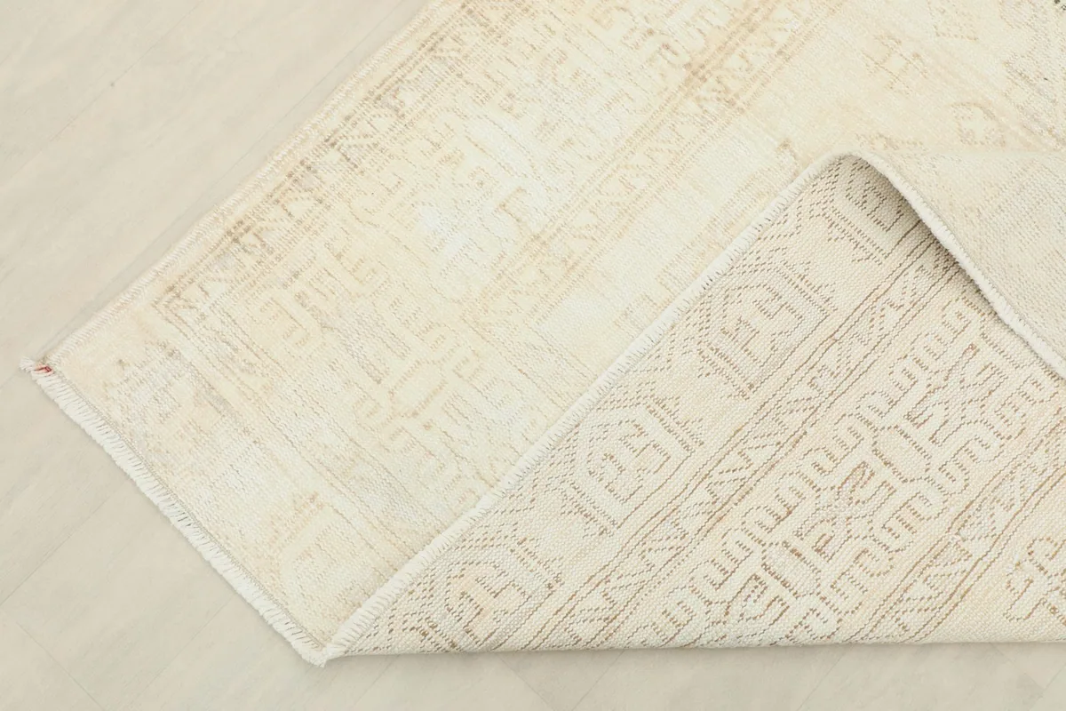 Corner of the rug folded to show the cotton foundation and reverse side
