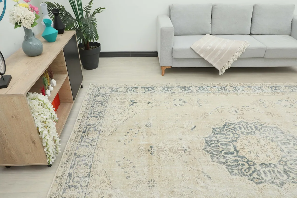 Close-up view of the vintage rug in a living room, showing the beige field and gray border