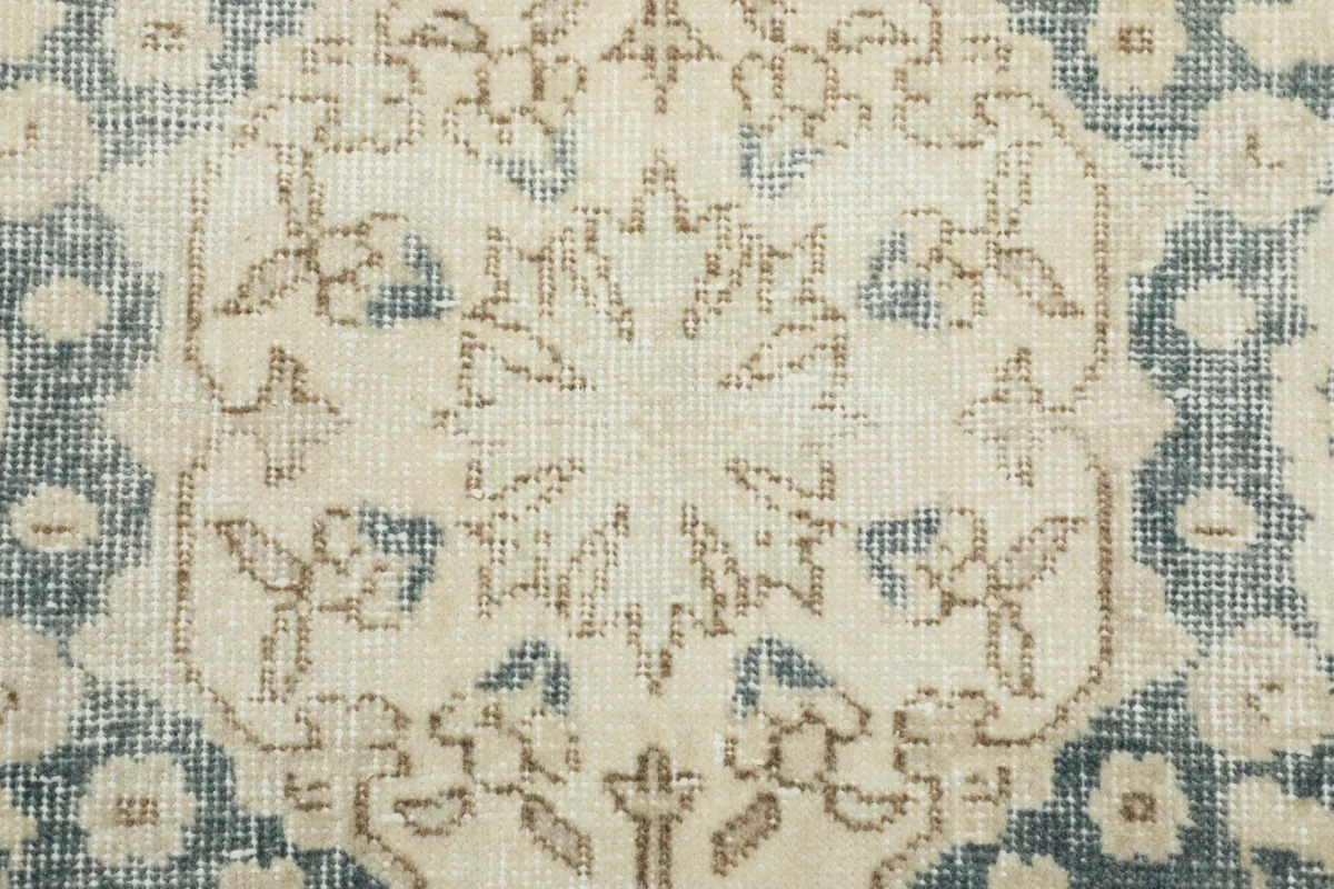 Close-up of the rug's surface, showing the subtle floral details within the beige and gray pattern