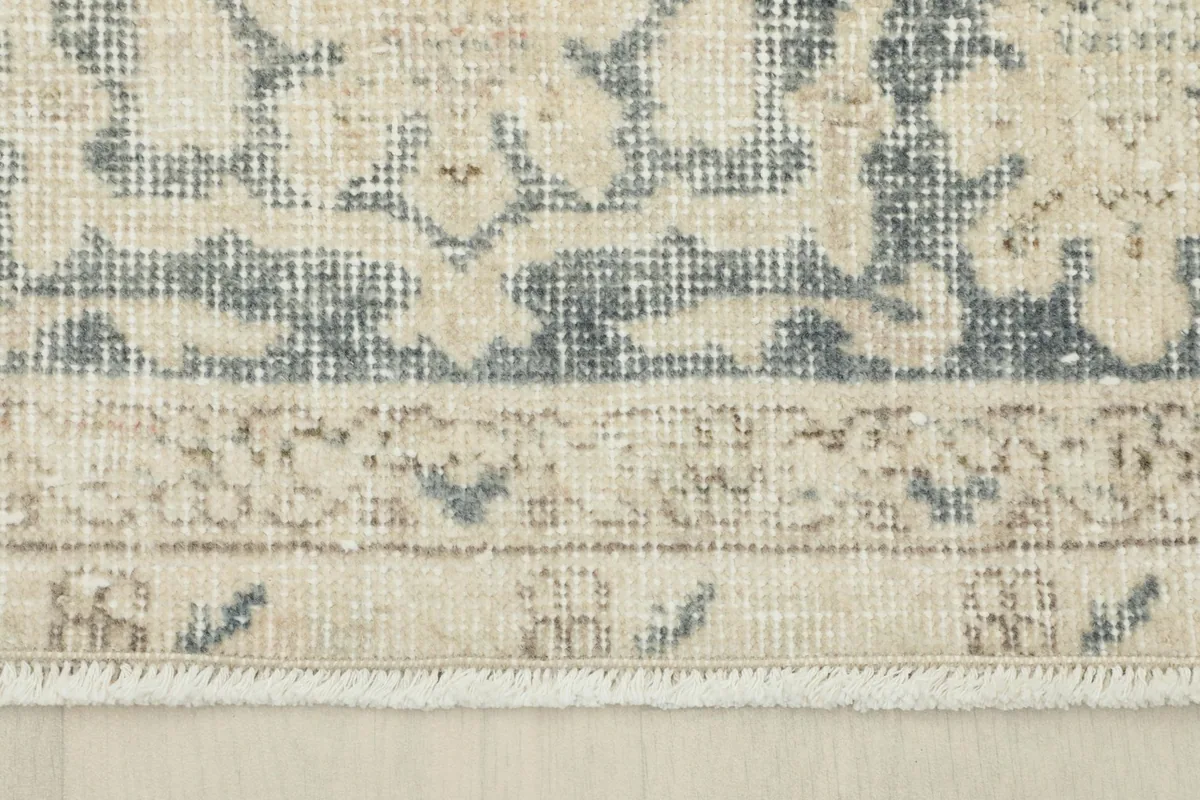 Close-up of the rug's border and fringe, showing the hand-knotted texture and slight wear