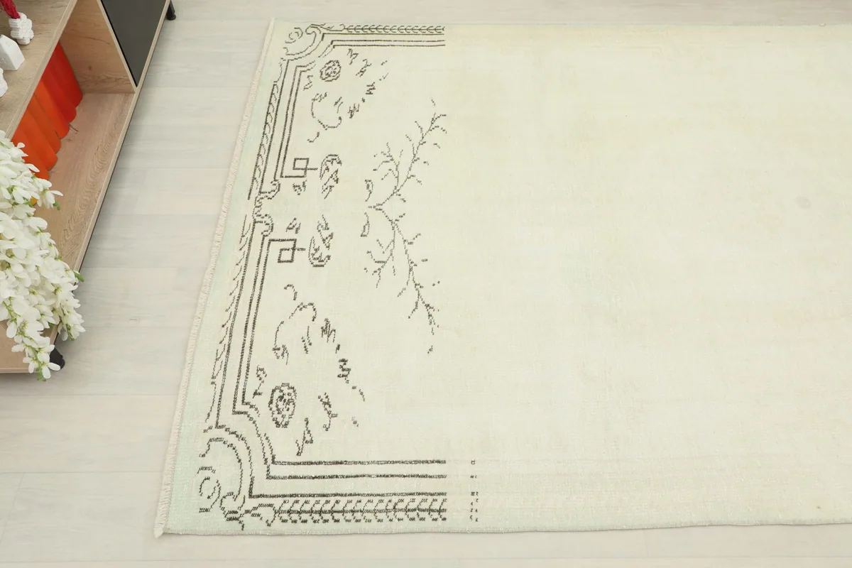 Close-up of the gray geometric and floral border pattern on one end of the ivory vintage rug.