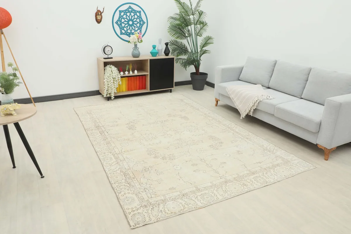 Ivory vintage Anatolian rug in a modern living room setting with a gray couch and light flooring.
